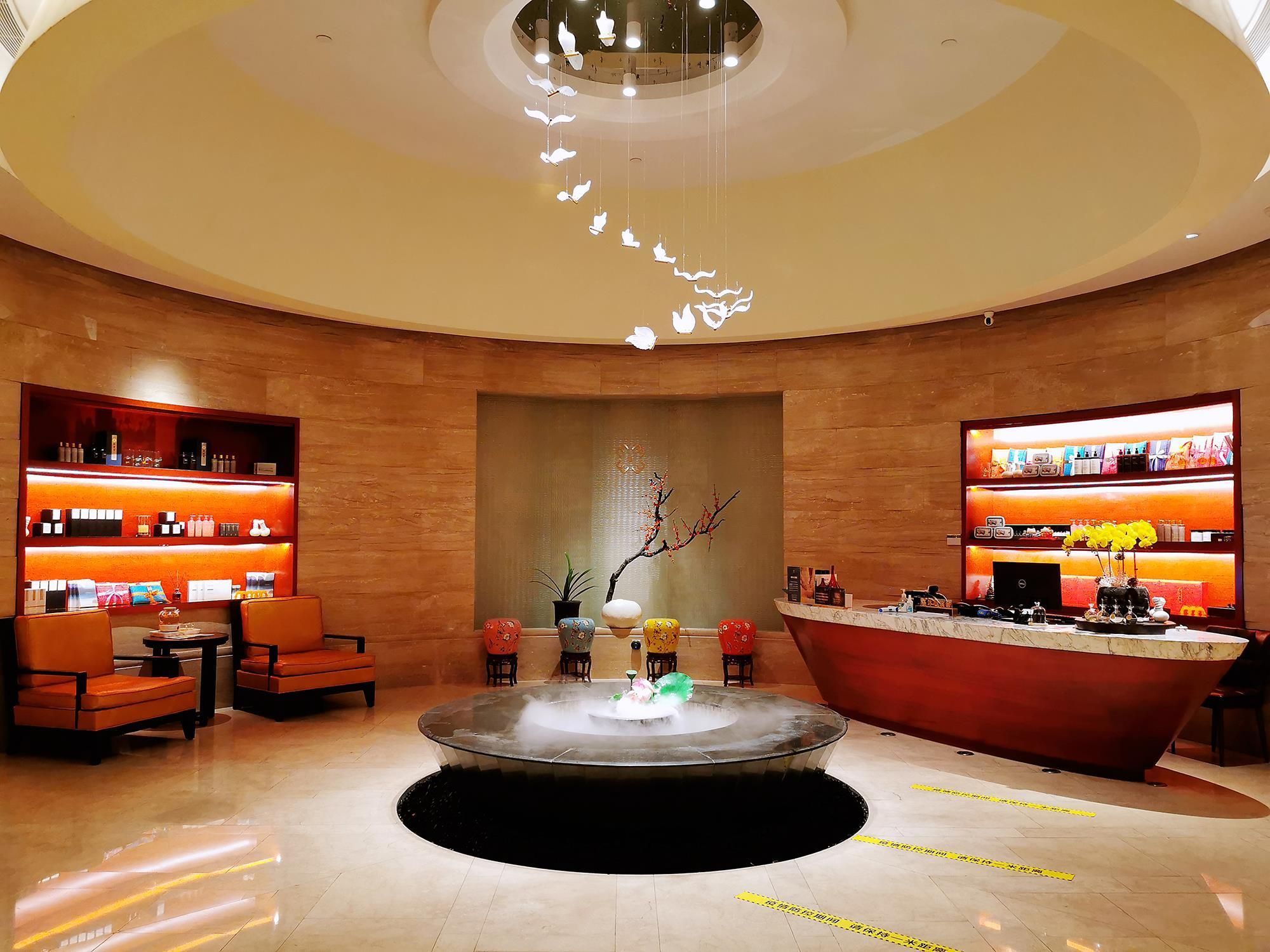 A lobby with a central fountain, seating area, and two large display shelves.