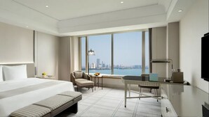 A modern hotel room with a large bed, a desk, a chair, and a view of the city skyline. - Kempinski Hotel Suzhou (Suzhou)