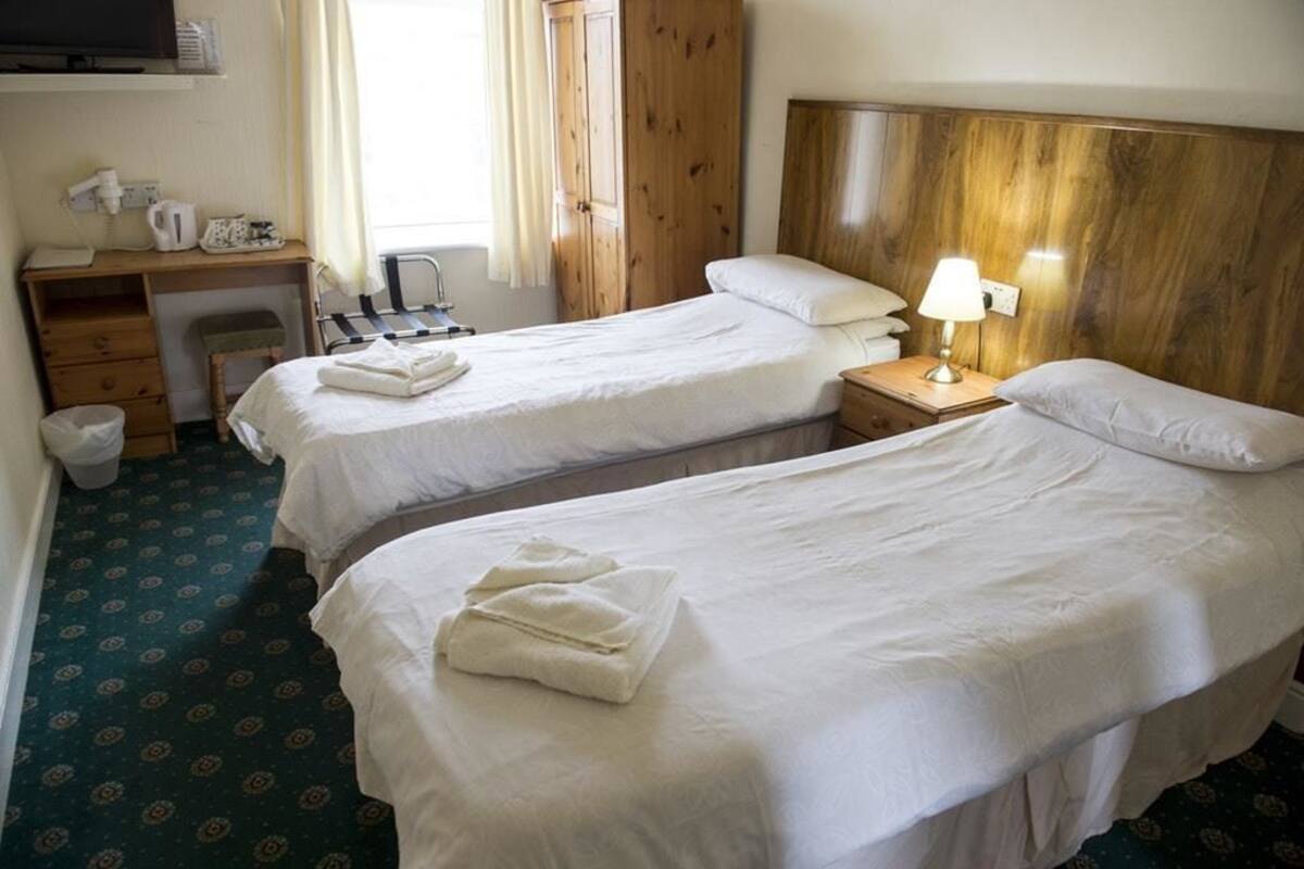 Hotellihuone, jossa on kaksi sänkyä, työpöytä, tuoli ja televisio.