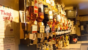 Un bar avec une variété de bouteilles d’alcool et une pancarte remerciant les clients.