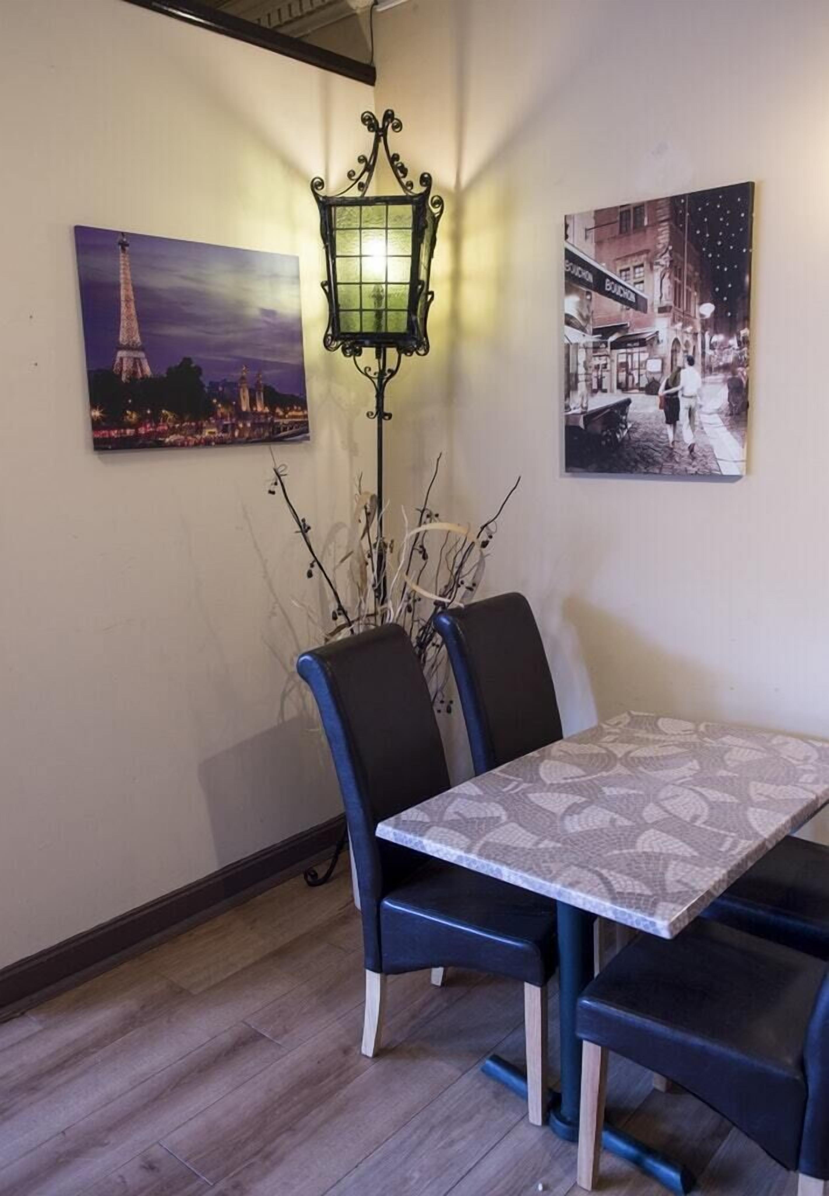 Un comedor con una mesa y sillas, una lámpara decorativa y dos cuadros colgados en la pared.