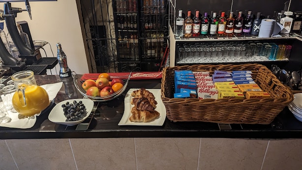 Un buffet de petit-déjeuner comprenant des fruits, des viennoiseries et des boissons.