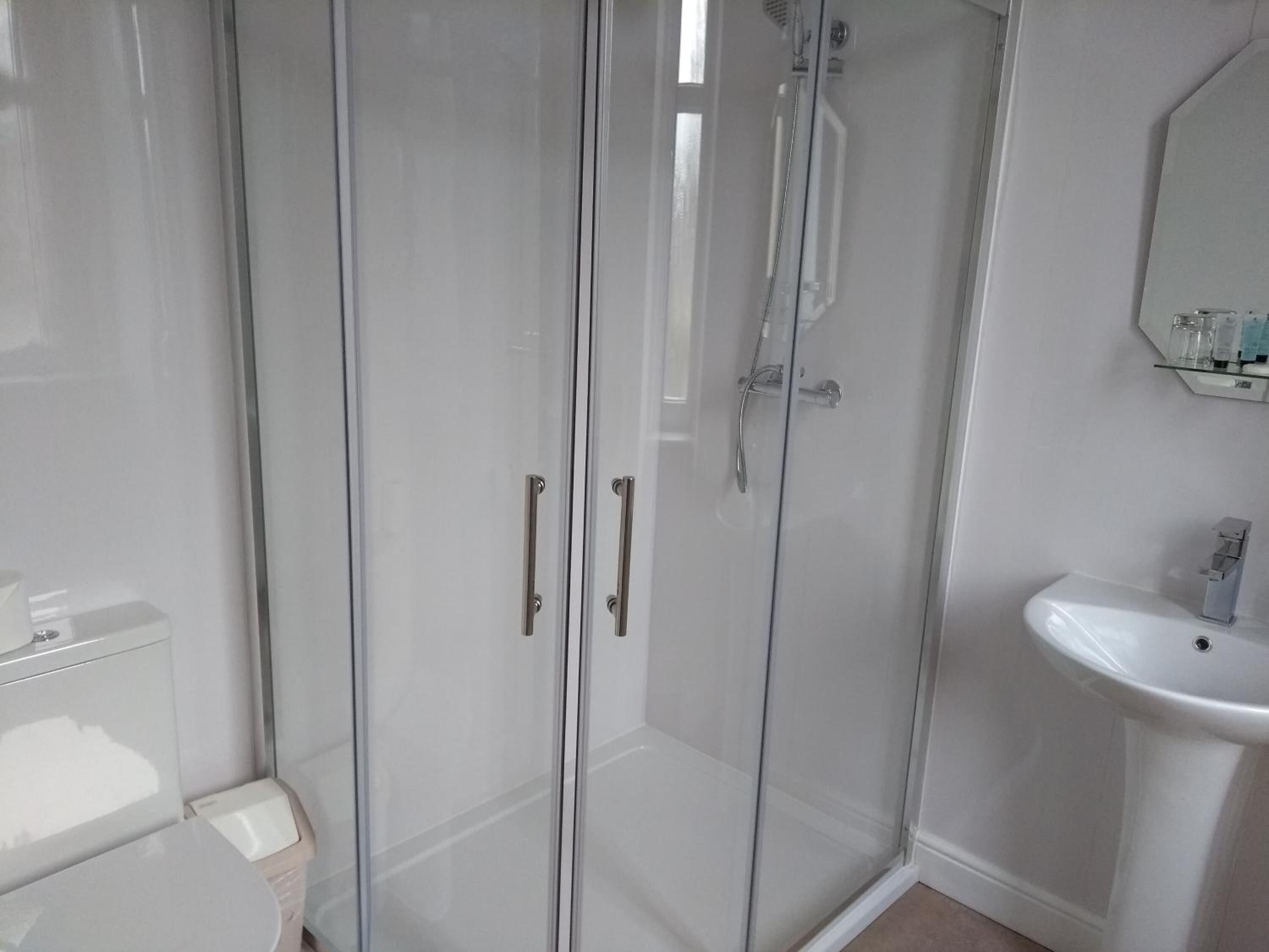 Een moderne badkamer met een douchecabine van glas, een wit wastafelmeubel en een toilet.