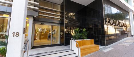 A modern building with a glass facade, a wooden bench outside, and the name "EVOLUTION" on the entrance.