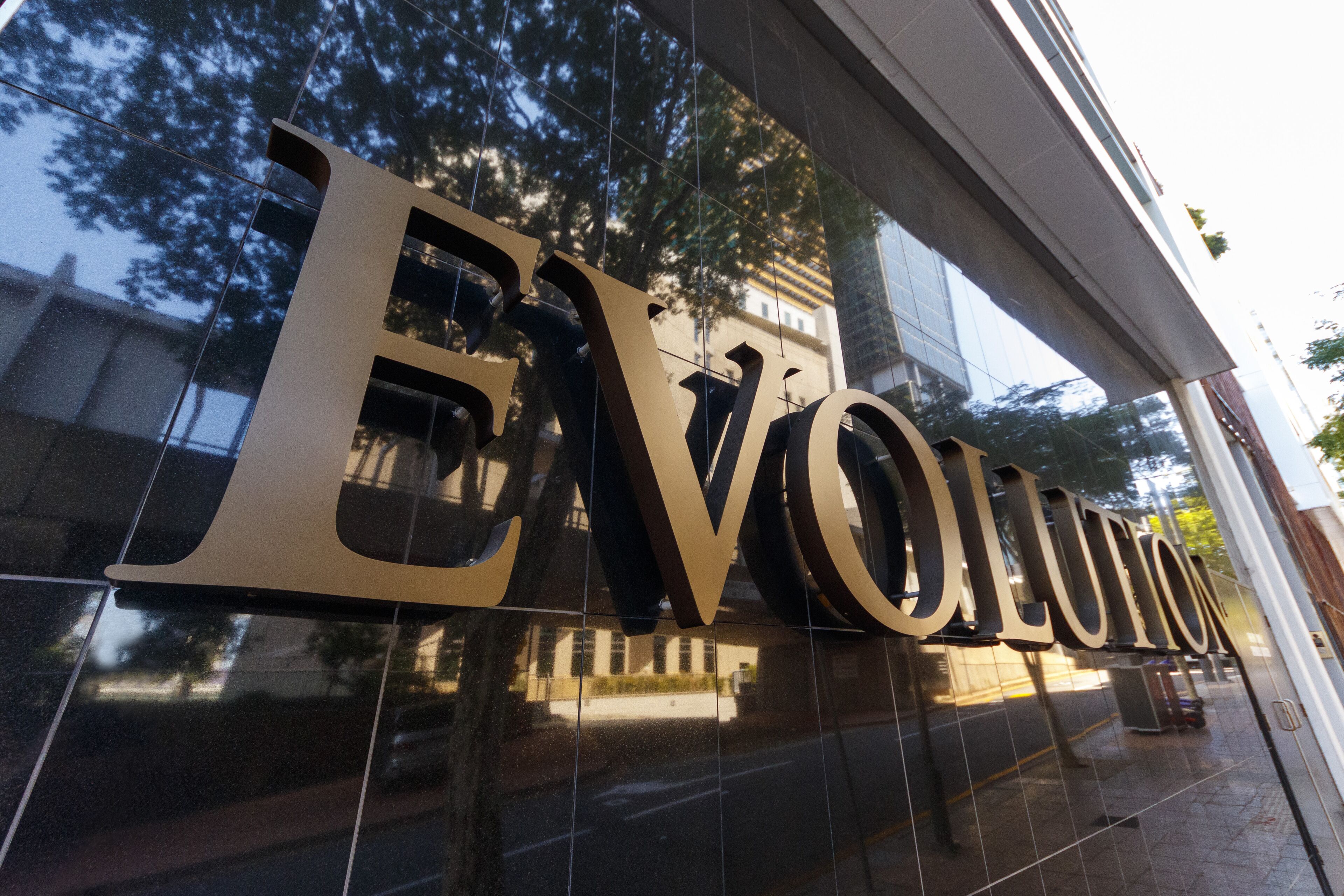 Large, reflective letters spelling "EVOLUTION" on a building facade.