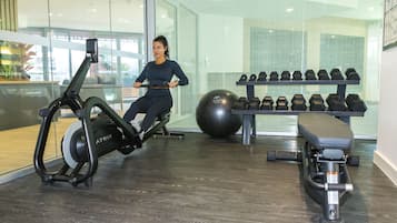 Een sportschool met cardioapparatuur, gewichten en een hometrainer.