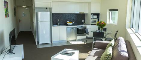 Une cuisine moderne avec des meubles blancs, un plan de travail noir et un coin repas comprenant une table et des chaises.