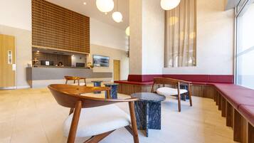 Un interior moderno con muebles de madera, mesas de mármol y una zona de estar con cojines rojos.