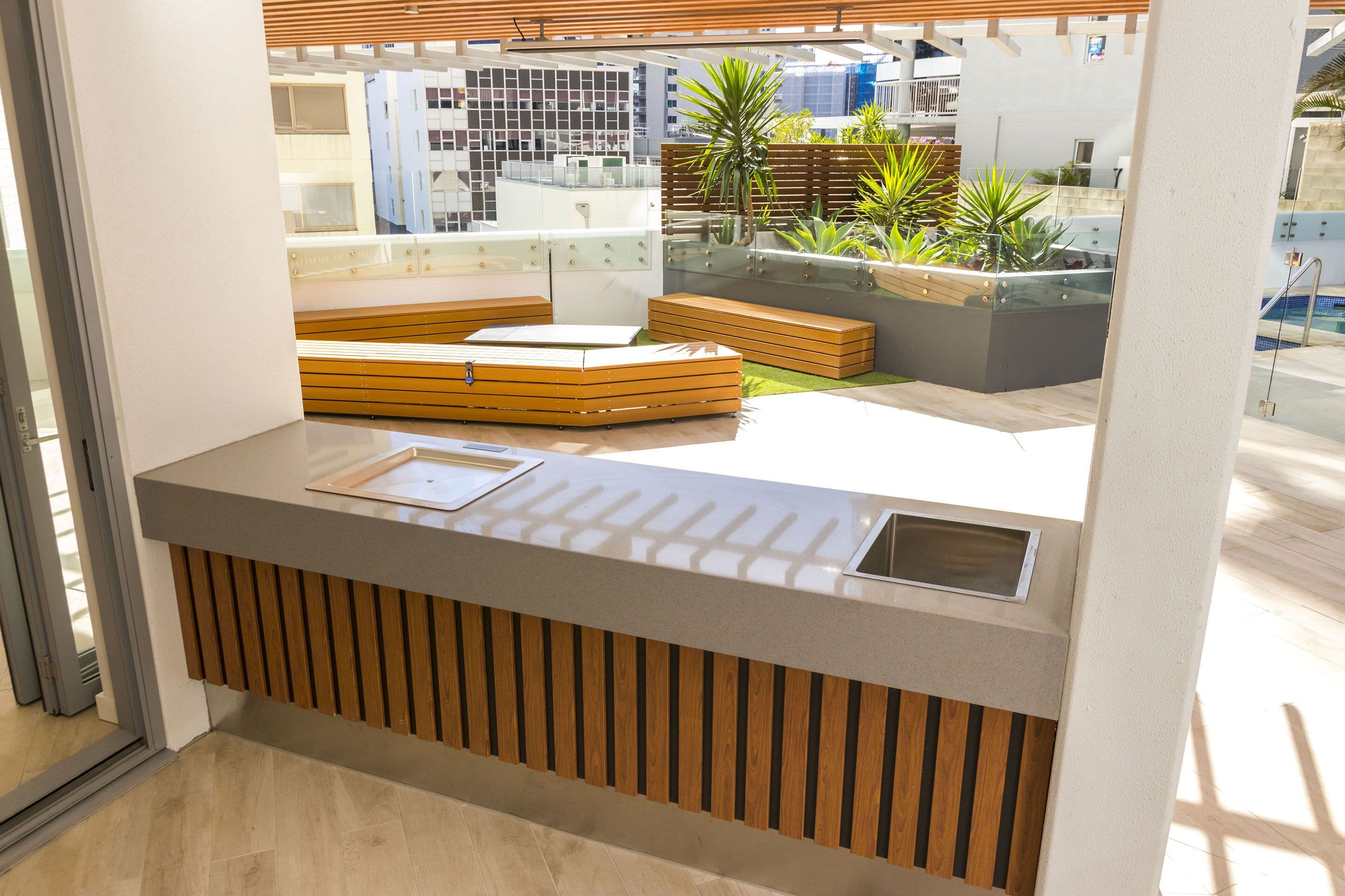 A modern reception area with a wooden bench, a glass partition, and a view of a pool and greenery.