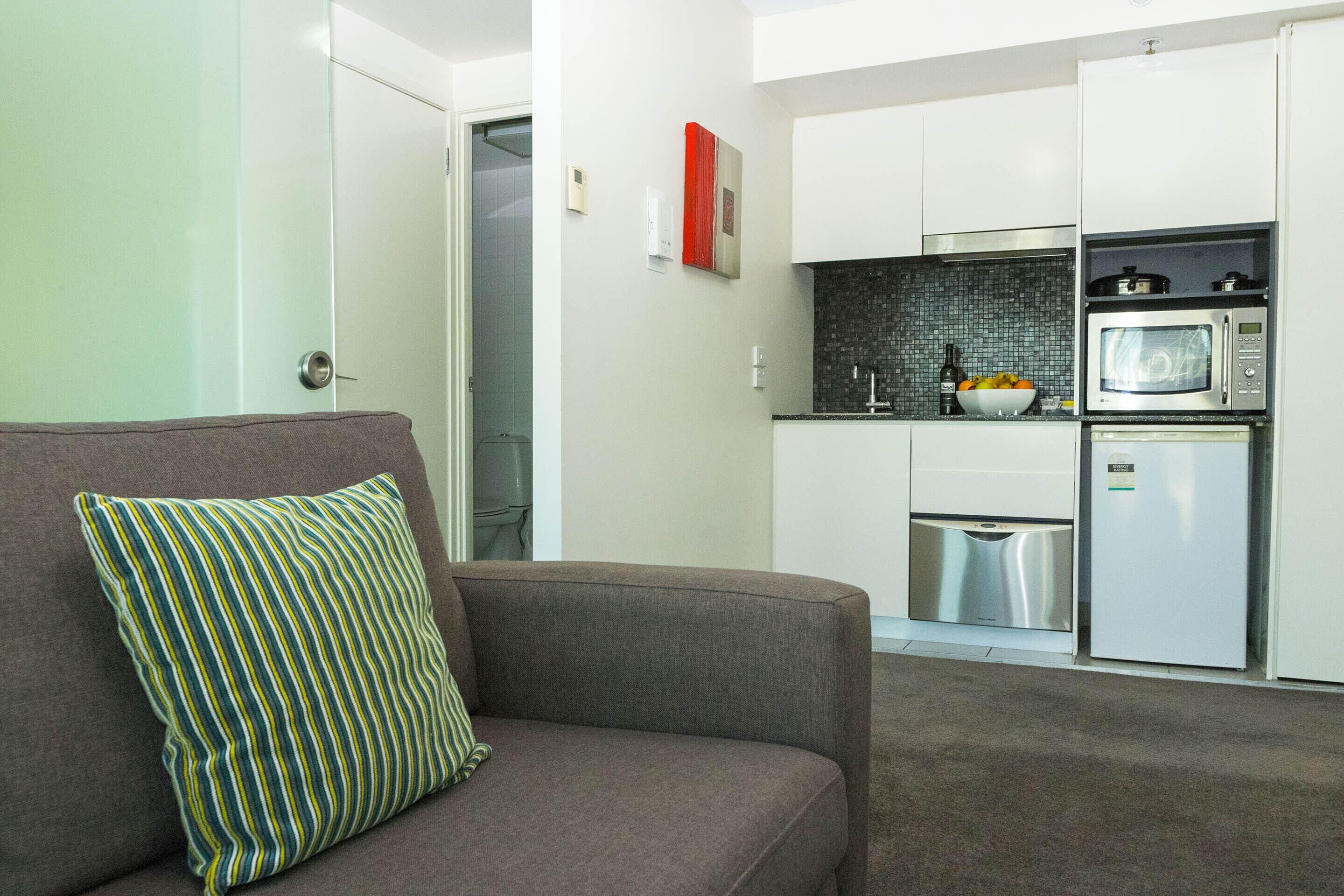 Una cocina moderna con armarios blancos, microondas y refrigerador de acero inoxidable.