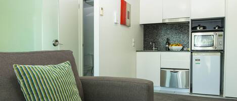 Una cocina moderna con armarios blancos, microondas y refrigerador de acero inoxidable.