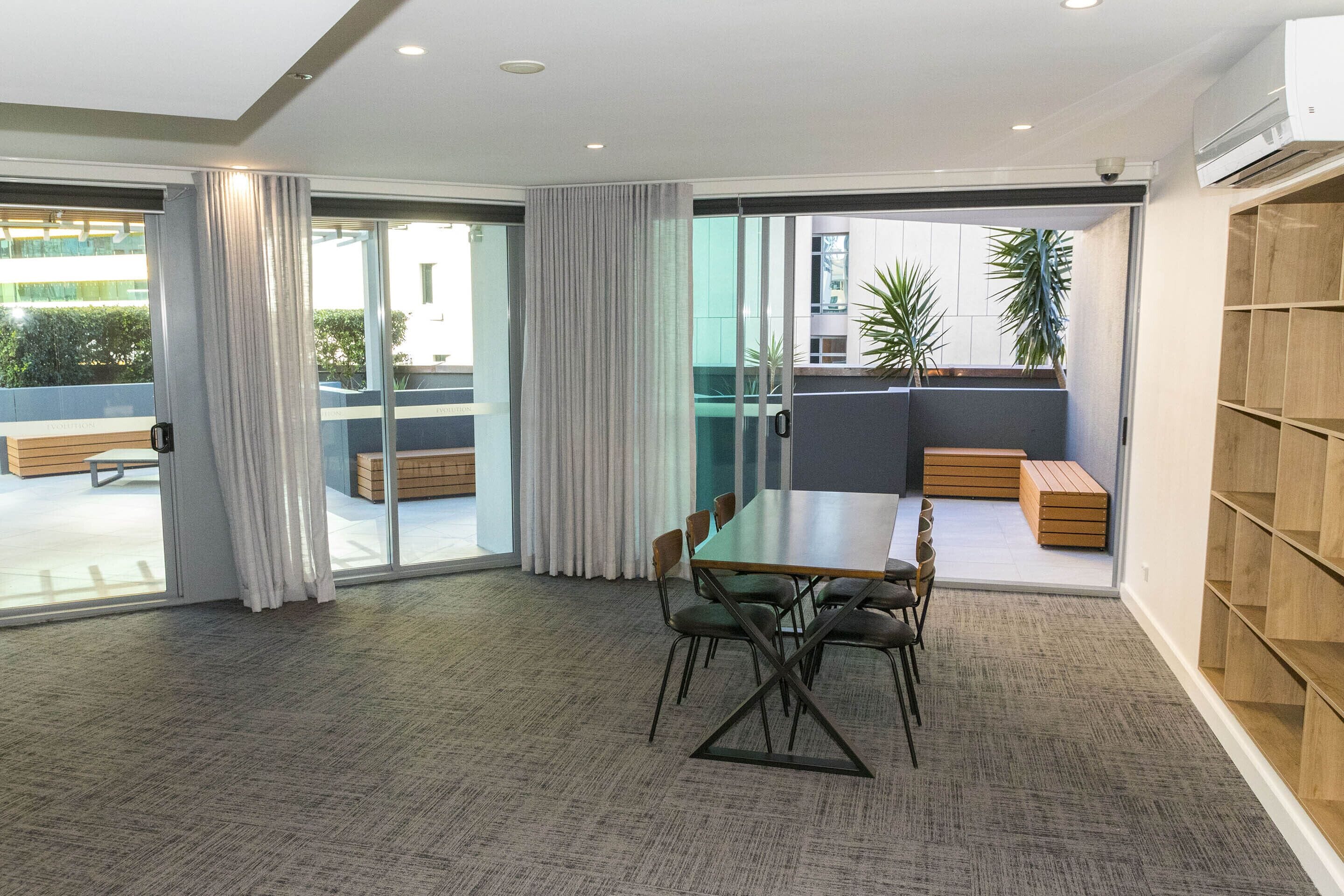 A modern meeting room with a glass partition, a wooden table, and chairs.