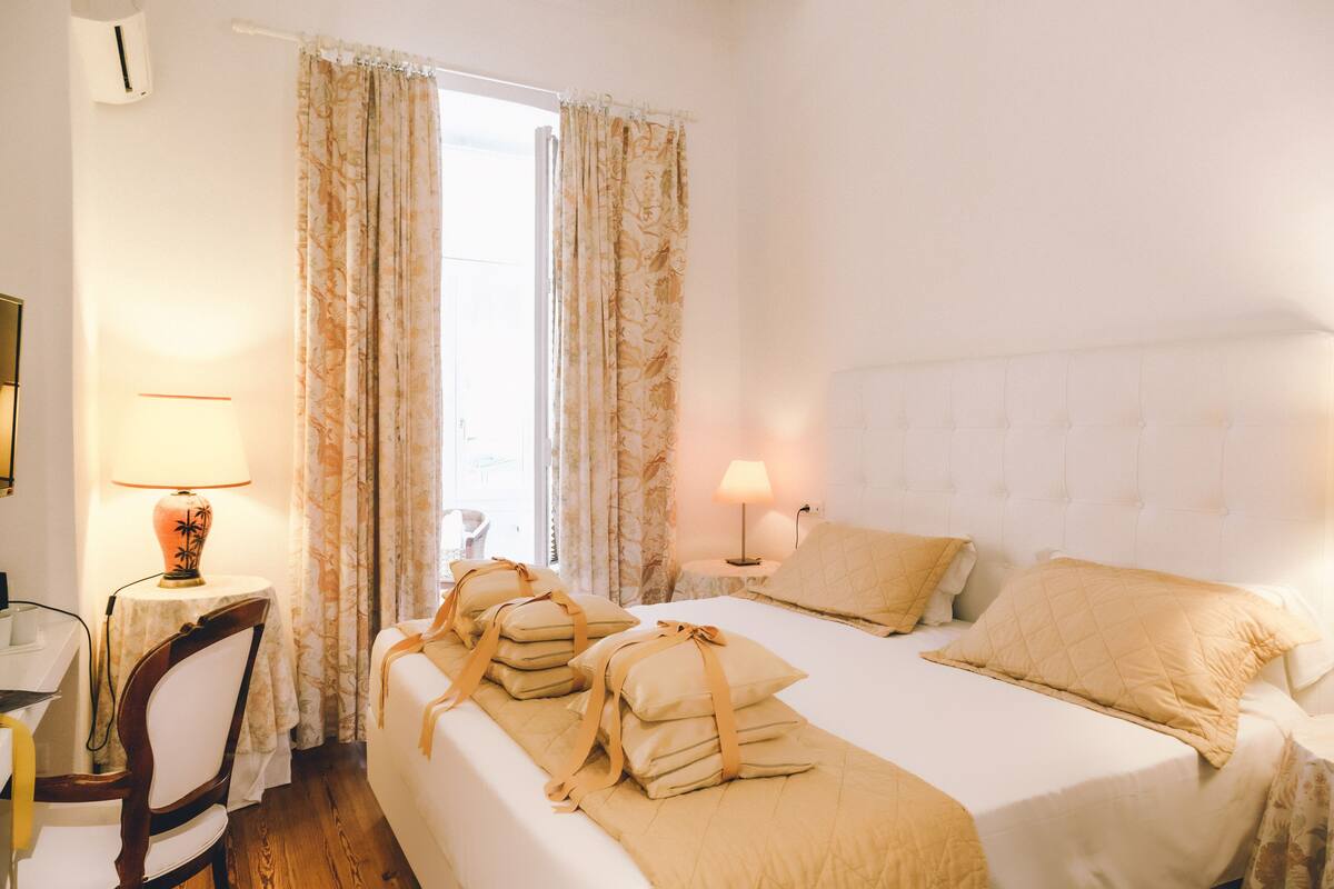Una habitación de hotel con una cama, dos lámparas de noche, una silla y una mesa con lámpara.