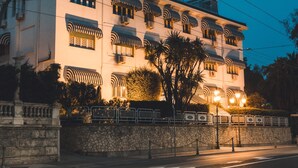 Un hôtel à plusieurs étages doté de balcons, d’un mur en pierre et donnant sur la rue.