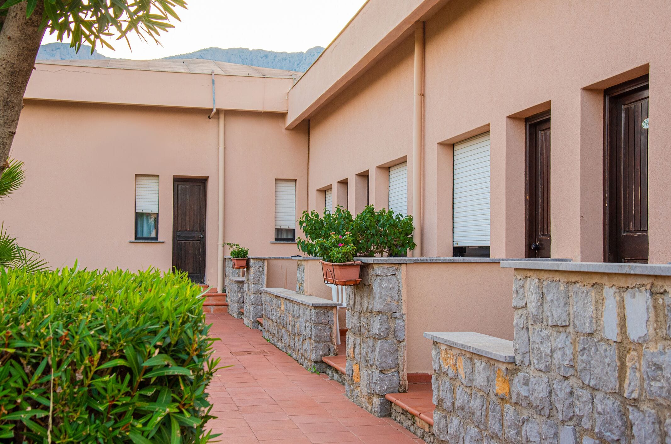 Un edificio con un vialetto in pietra, piante in vaso e una porta.