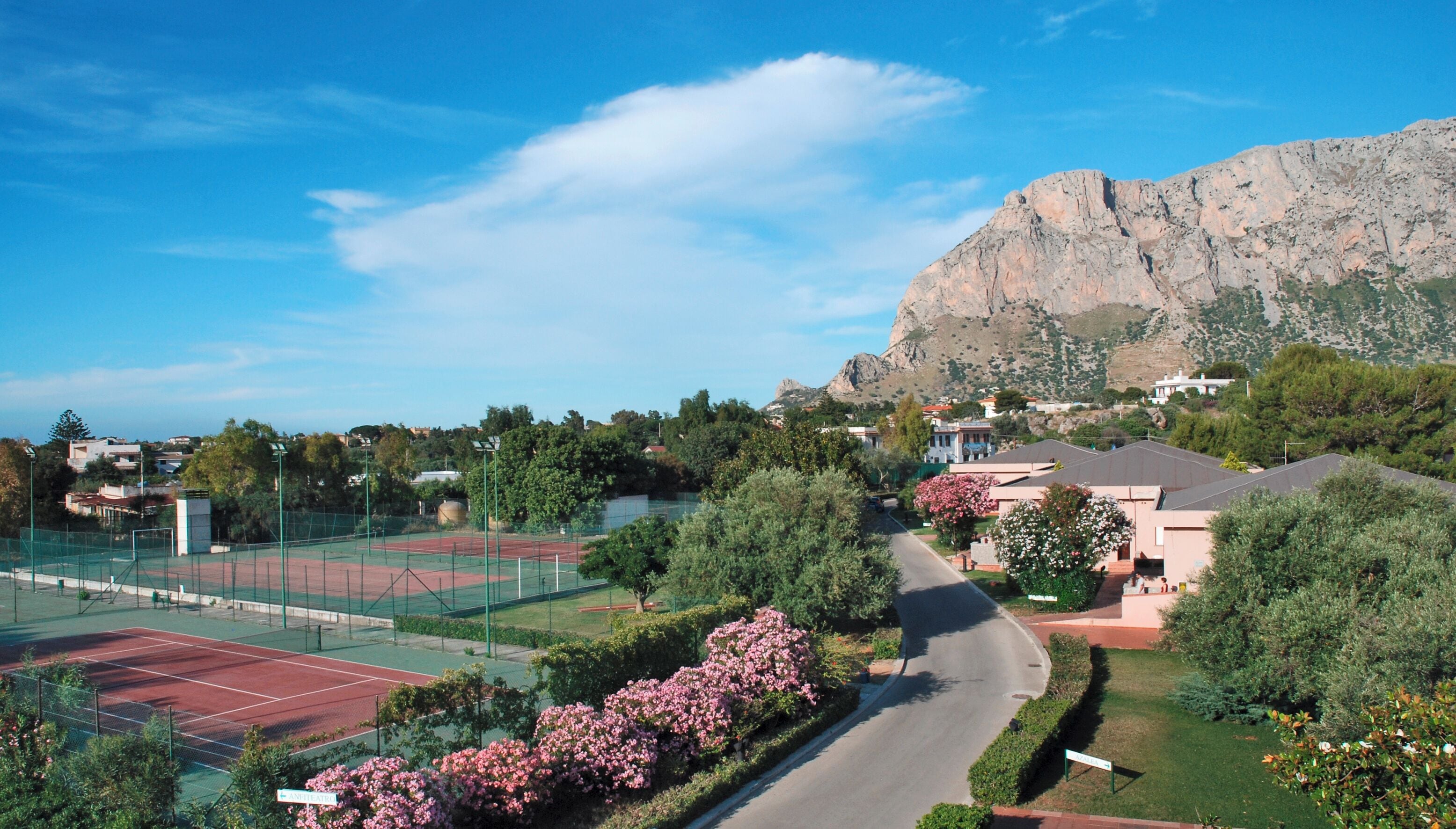 A tennis court, a road, and a mountain in the background.