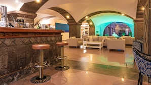 Una zona de bar con taburetes, una barra y un área de estar con sofás y una mesa de centro.
