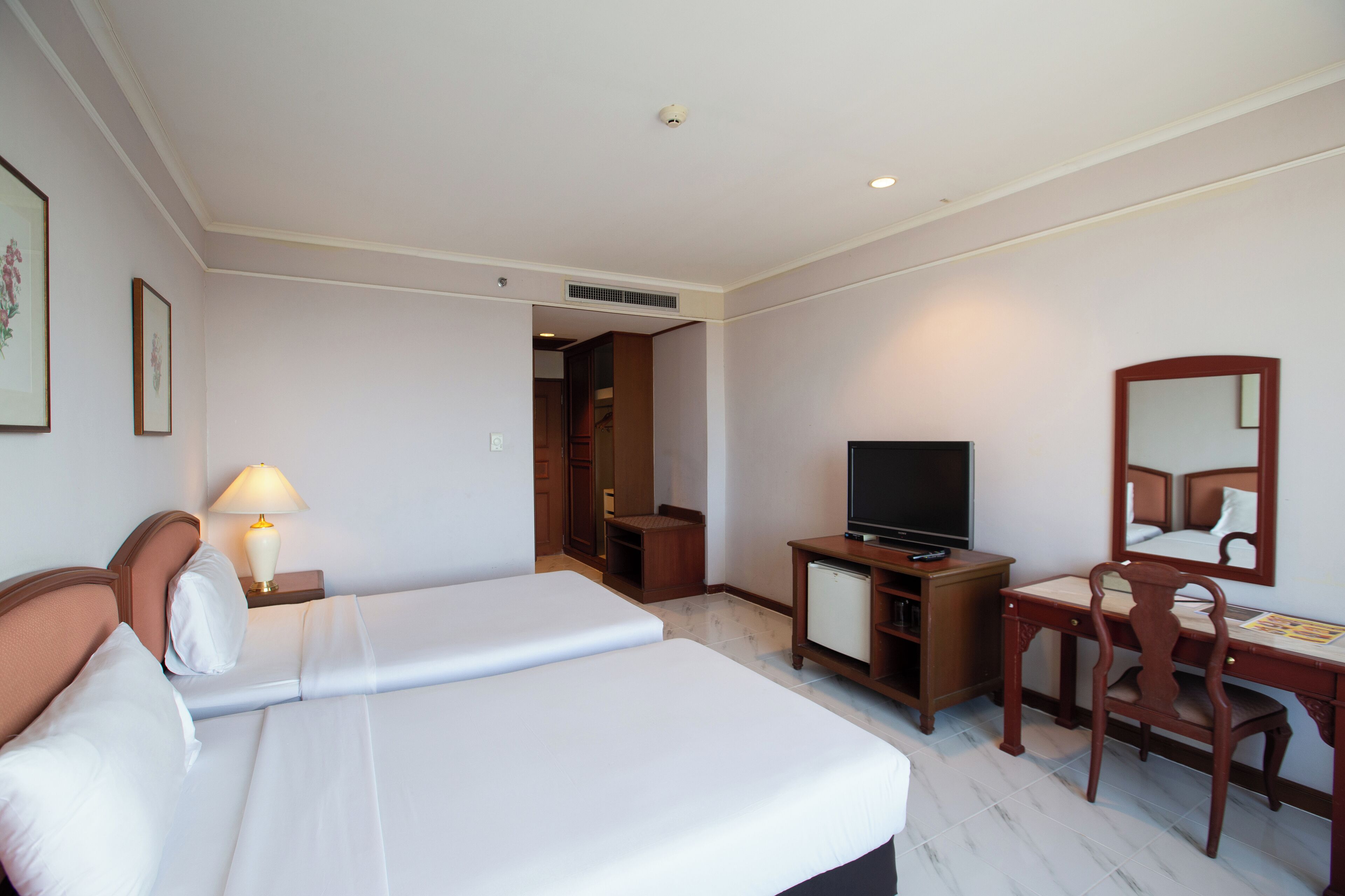 Ein Hotelzimmer mit einem Bett, einem Schreibtisch mit Stuhl, einem Fernseher und einem Spiegel.