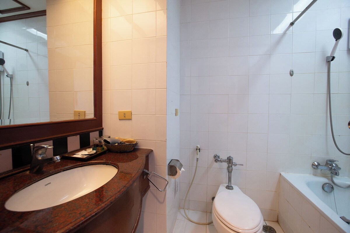 A bathroom with a sink, mirror, toilet, and shower.