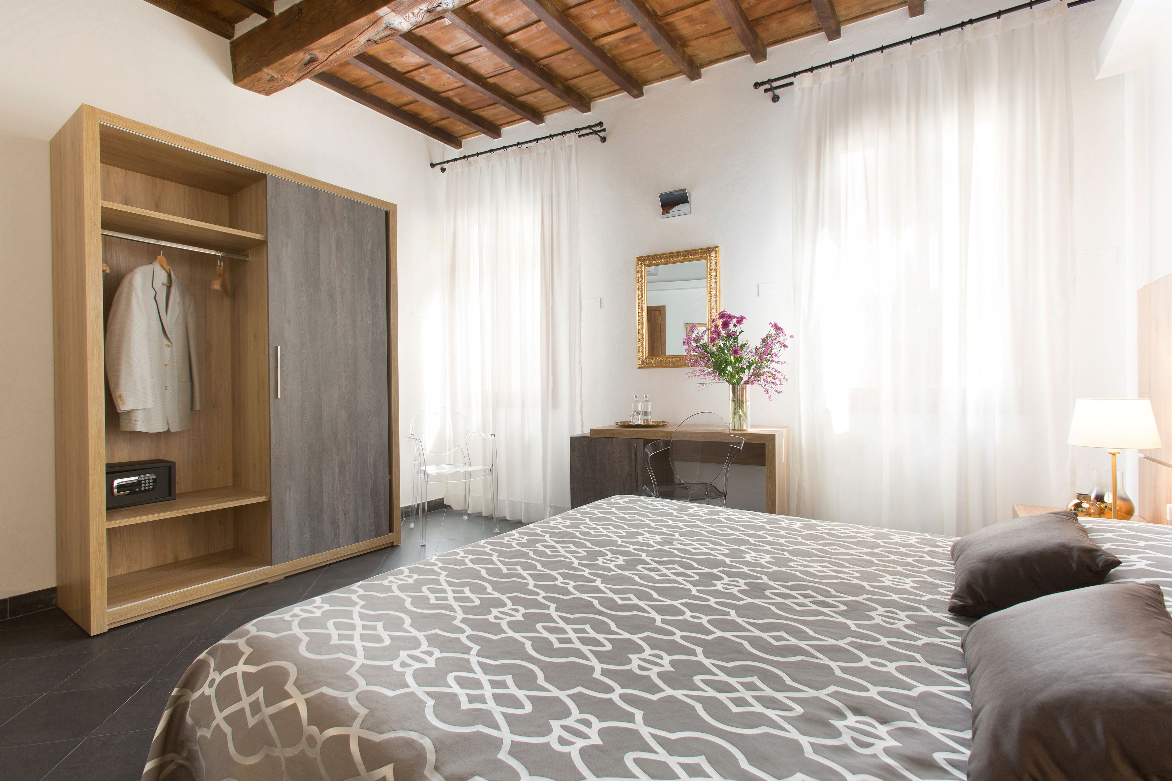 A bedroom with a bed, a wardrobe, a desk, and a mirror.