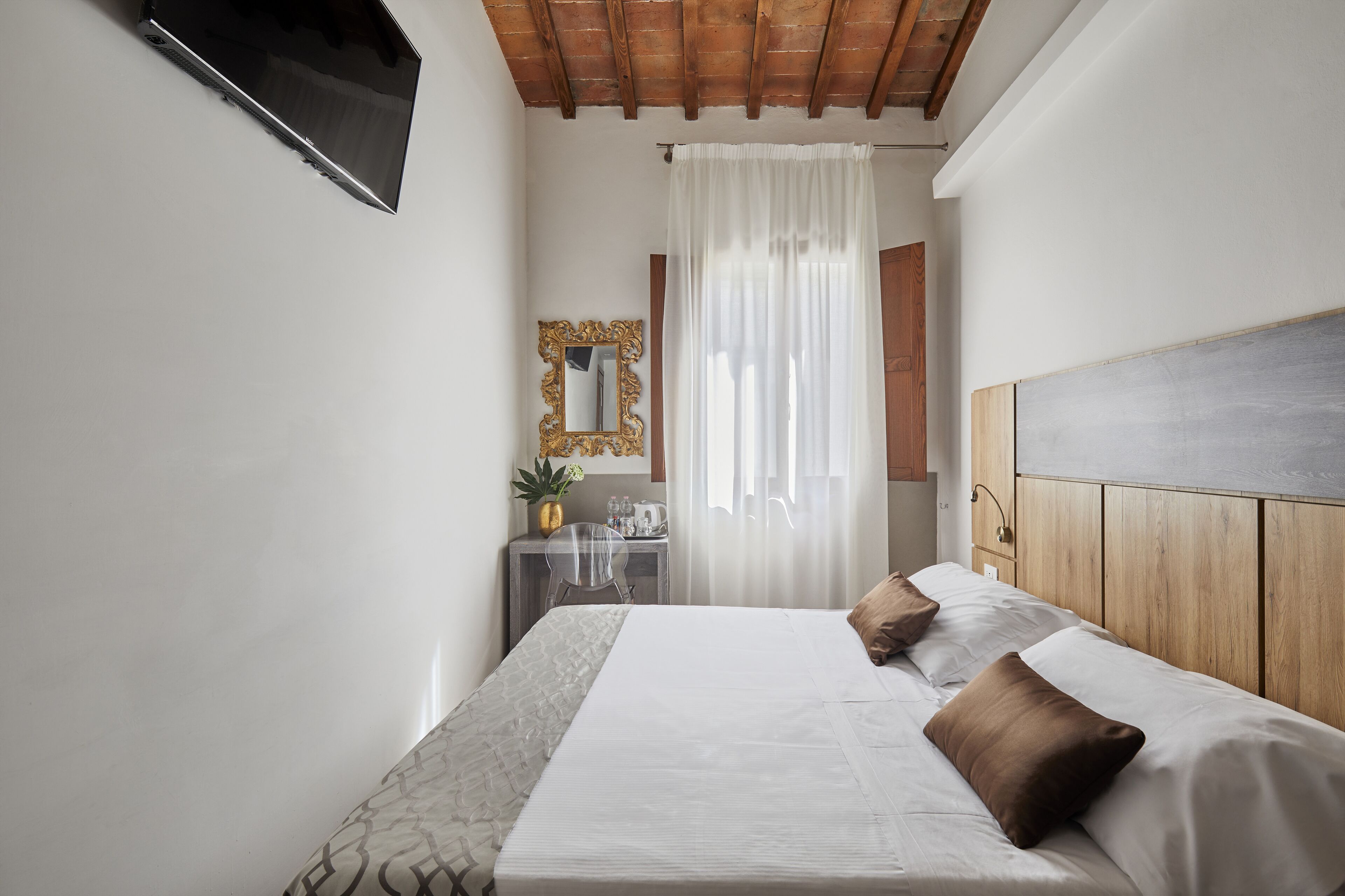 Een slaapkamer met een bed, een bureau, een spiegel en een televisie.