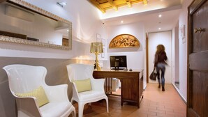 A hotel lobby with two white chairs, a wooden desk, a lamp, and a large mirror. - Sette Angeli Rooms (Florence)