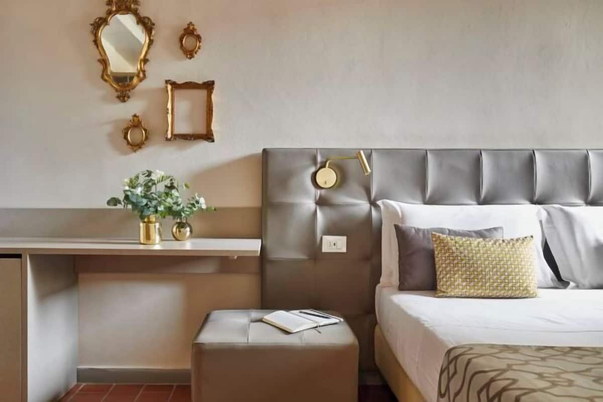 A bedroom with a bed, bedside table, and a small stool.