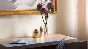 A wooden desk with a magazine, two gold vases, and a vase with pink flowers. - Sette Angeli Rooms (Florence)
