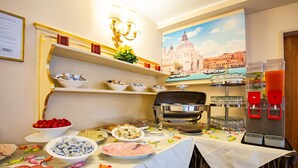 Montaje de bufé con diversos alimentos, una máquina de café y una pared decorativa con un paisaje urbano.