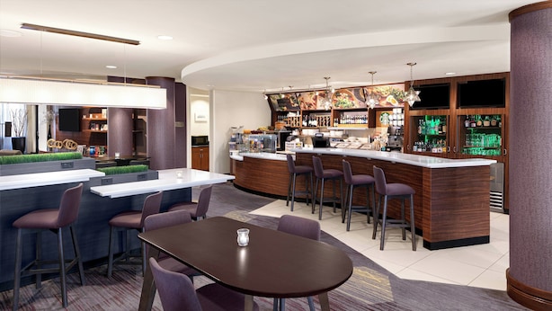 A modern bar area with a counter, bar stools, and a seating area with a table and chairs.