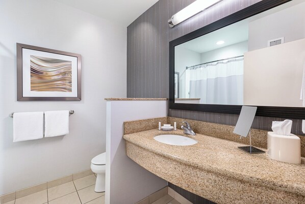 Un baño moderno con encimera de granito, un lavabo, un espejo y una obra de arte enmarcada en la pared.