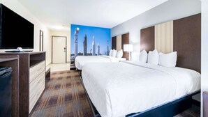A hotel room with a large bed, a desk, a television, and a cityscape mural on the wall. - Clarion Pointe Madison Huntsville (Madison)
