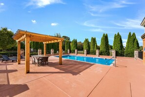 A pool area with a pergola, lounge chairs, and a table. - Clarion Pointe Madison Huntsville (Madison)