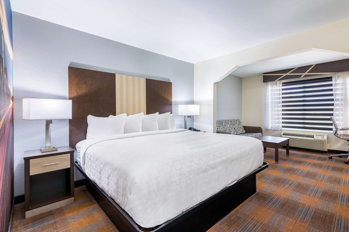 A hotel room with a large bed, bedside tables, a desk, and a chair.