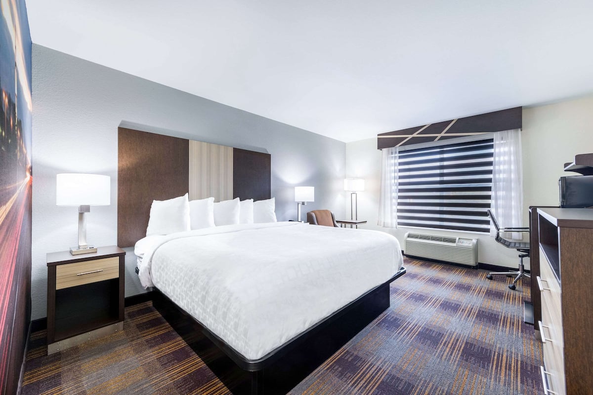 A hotel room with a large bed, bedside tables with lamps, a desk, and a chair.