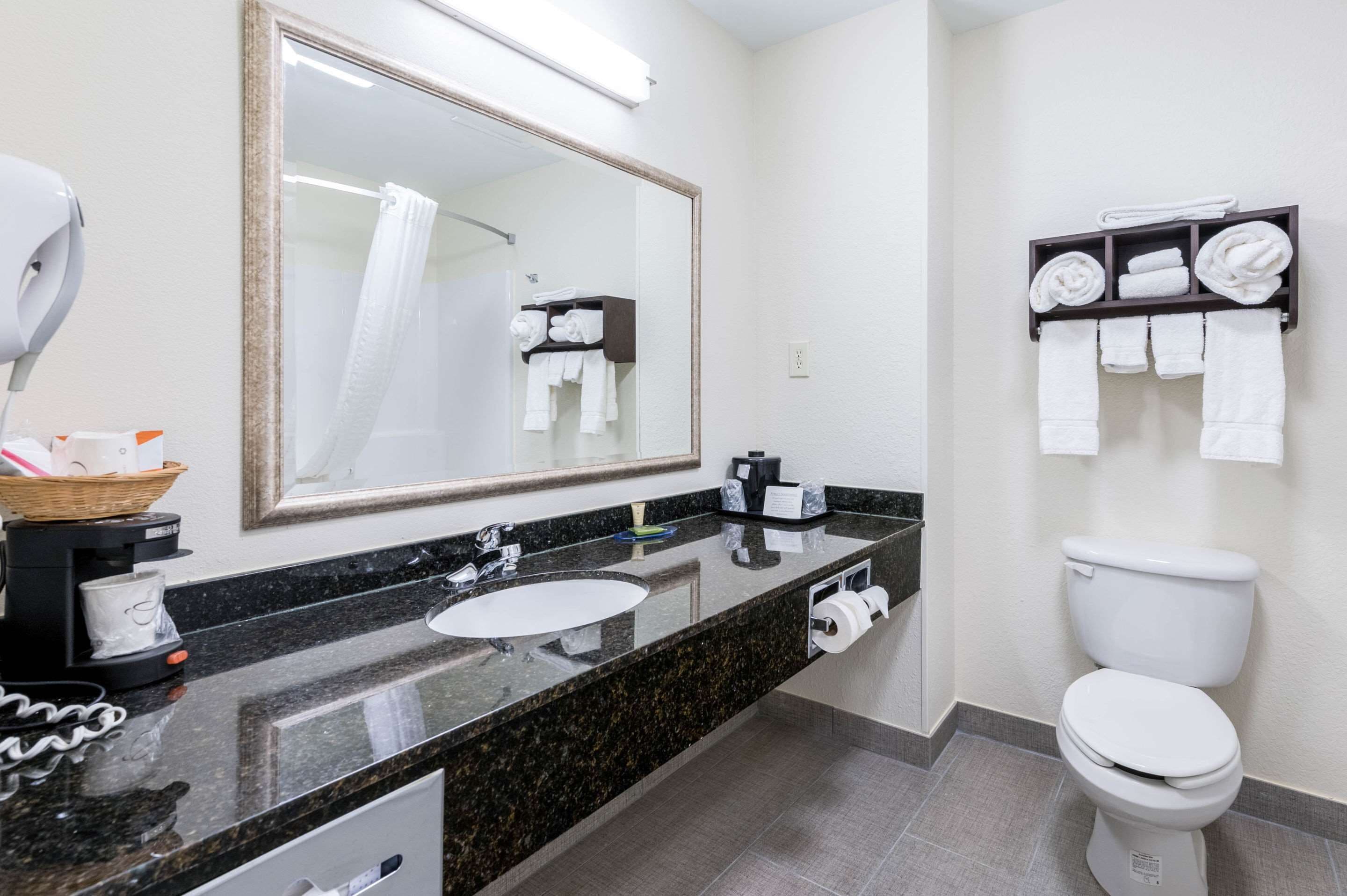 A modern bathroom with a large mirror, a sink, a toilet, and a towel rack.