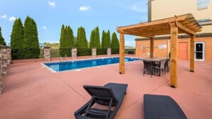 An outdoor pool area with lounge chairs and a pergola. - Clarion Pointe Madison Huntsville (Madison)