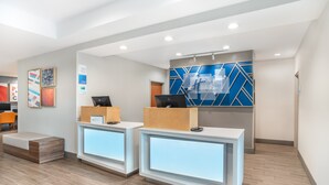 A reception area with two reception desks, a seating area, and a wall with geometric patterns.