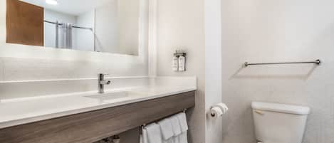 A modern bathroom with a white sink, mirror, and toilet.