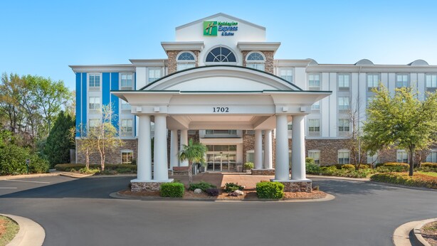 A Holiday Inn Express hotel with a prominent entrance, numbered 1702, and a clear sky above.