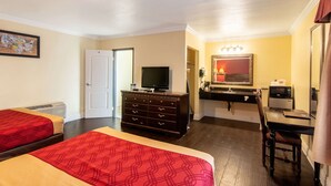 A hotel room with two beds, a dresser, a television, a desk with a chair, a microwave, and a sink.