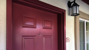 A red door with a keypad lock, a mailbox, and a street sign with the number 207.