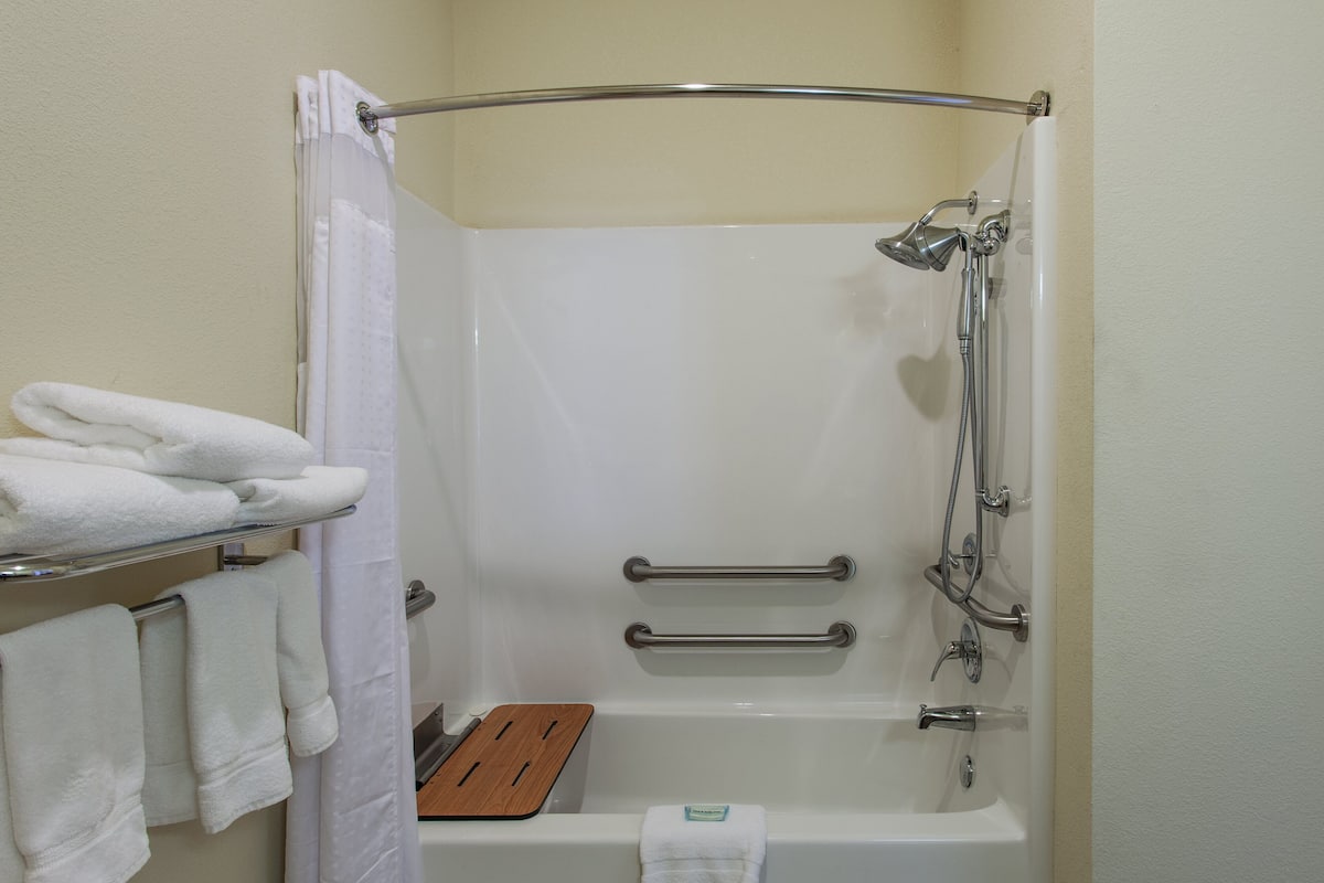 Eine Dusche mit Glastür, ein Holztablett und zwei Handtuchhaltern mit Handtüchern.
