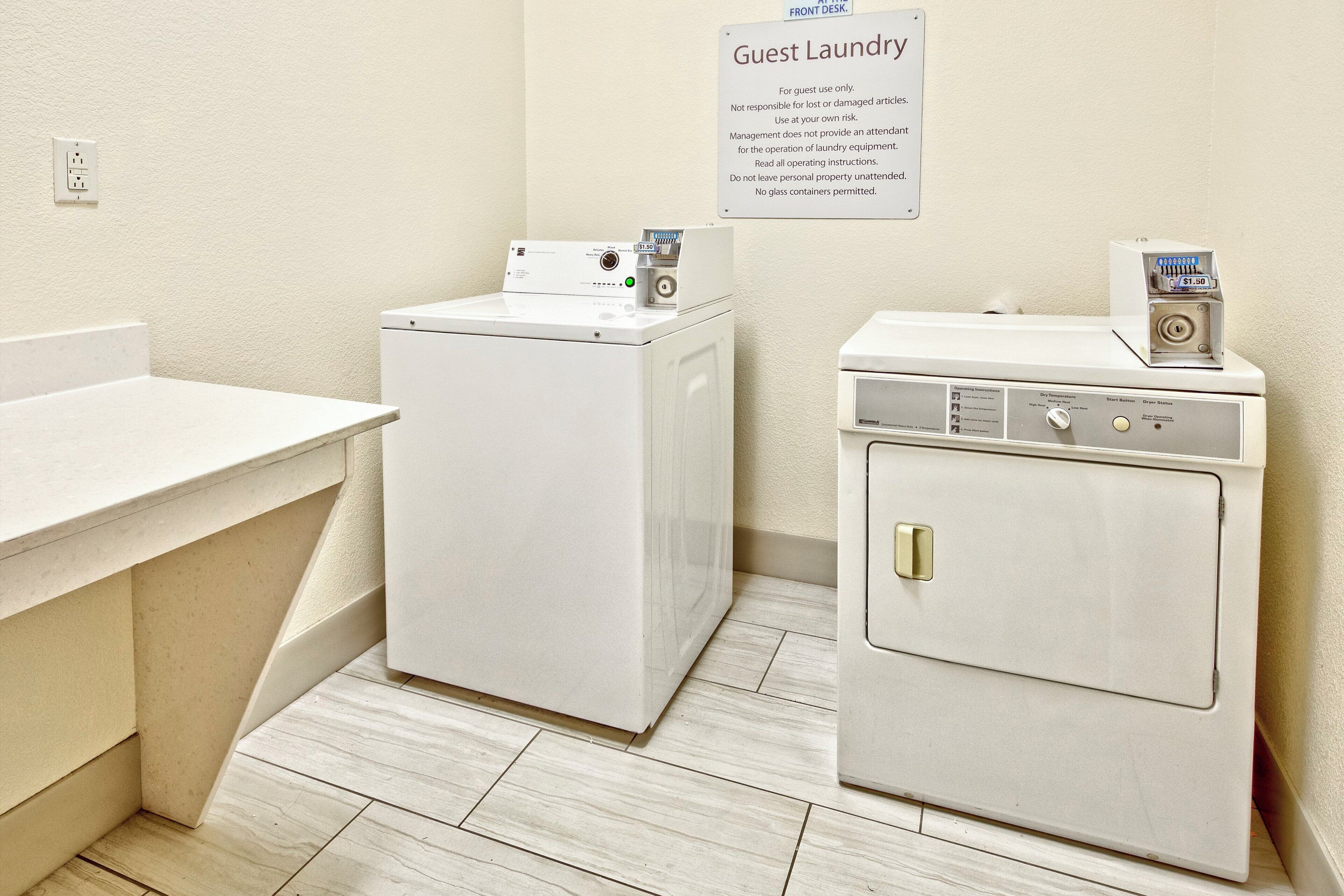 A laundry area with a front desk, a washing machine, and a dryer.