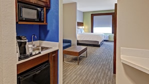 Habitación de hotel con kitchenette, una cama, un pequeño rincón de descanso y vistas al exterior.