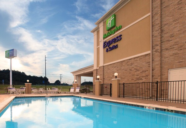 Un Holiday Inn Express & Suites con piscina, zona de estar al aire libre y fachada de ladrillo.