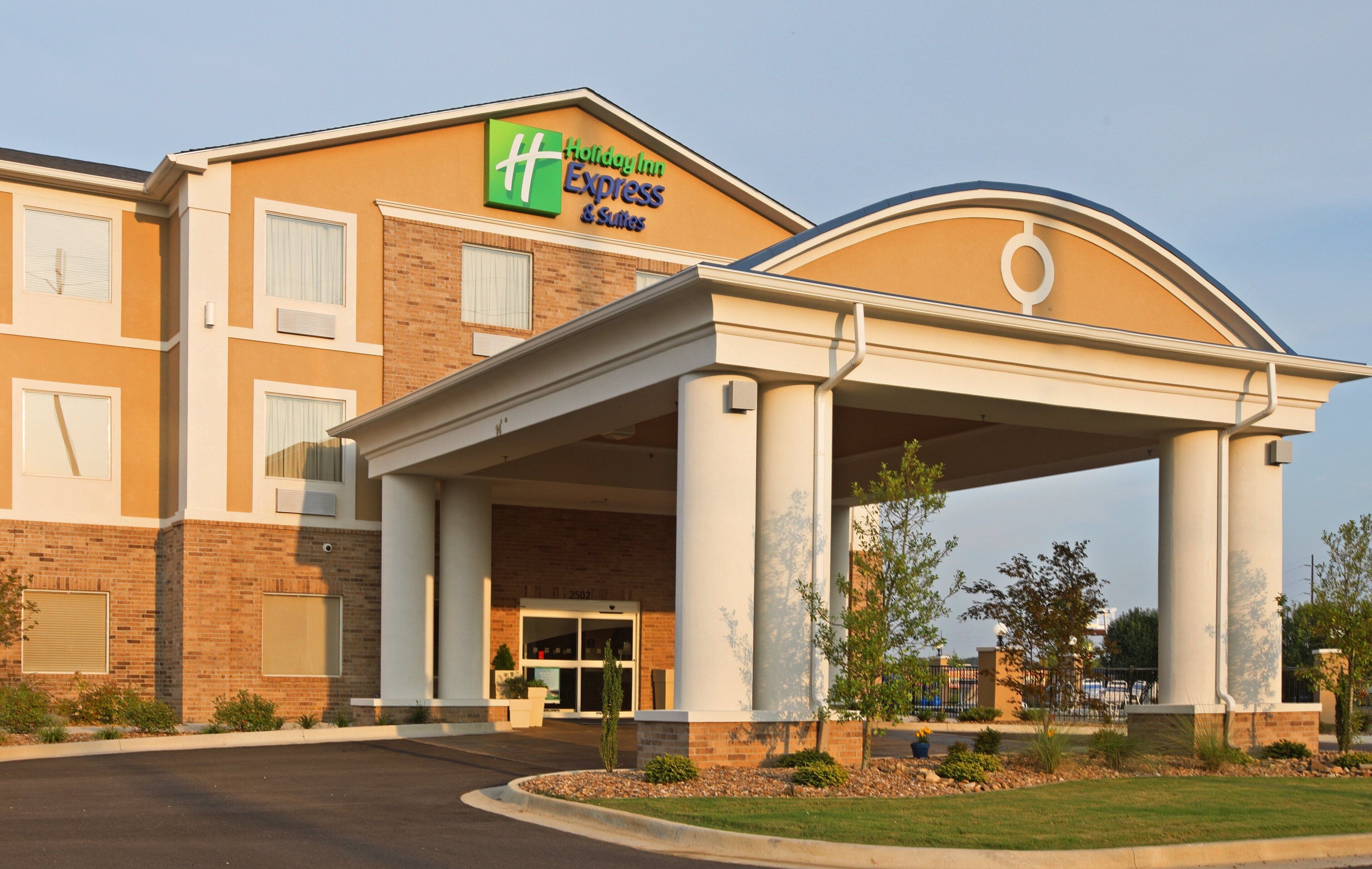 Edifício Holiday Inn Express com entrada coberta, fachada de tijolos e céu claro.
