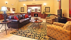 Amplia sala de estar con chimenea, sofás de cuero, alfombra estampada y televisor.