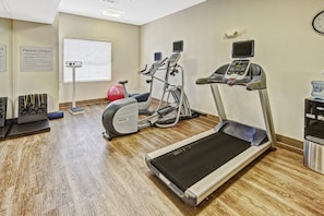Un gimnasio con cintas de correr, elípticas y una bicicleta estática.
