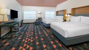 A hotel room with a bed, desk, chair, and a TV.